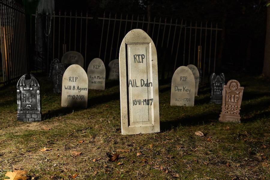 A picture of decorative headstones that say RIP with dates under it from 1807-1907 and people who have passed for the Haunted Arboretum